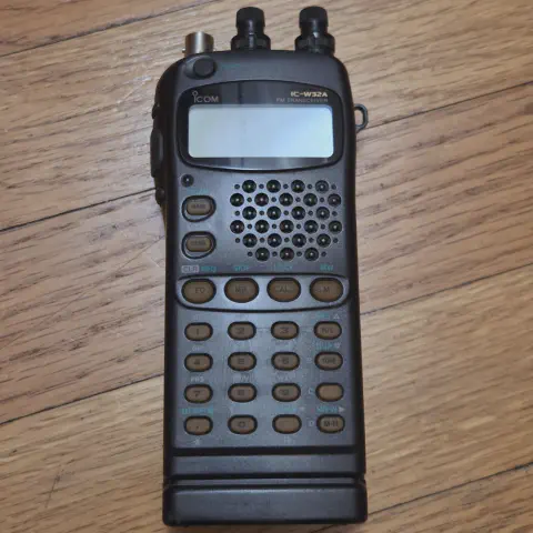 icom ic w32a front view showing bnc connector without antenna black smooth body two control knobs lcd disaplay control buttons numeric keypad function keys speaker grille