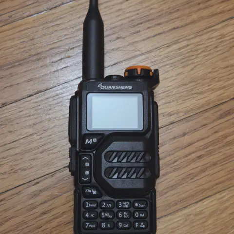 quansheng uvk5 with black antenna attached black textured body single control knob lcd display control buttons numeric keypad