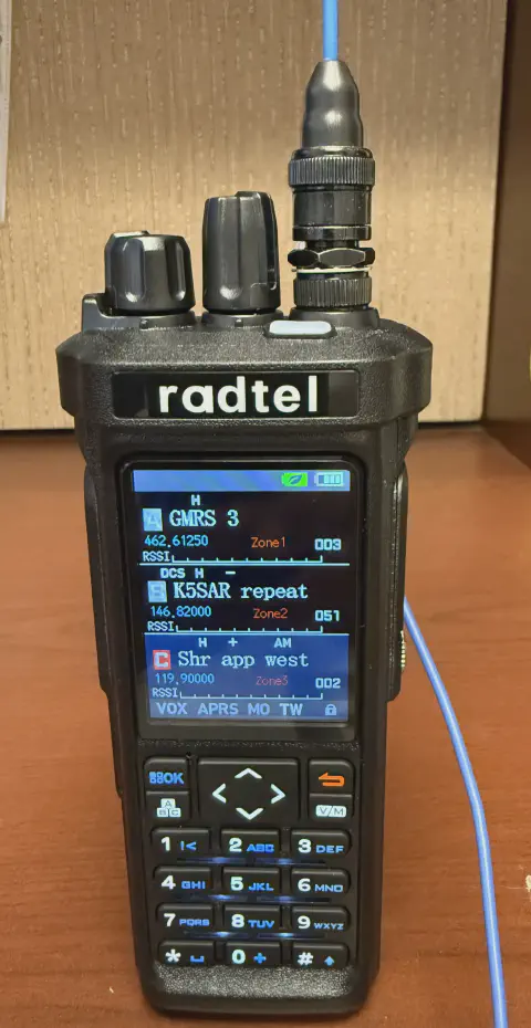 radtel rt 950 pro front view with signal strand adapter attached blue antenna and counter poise wire black textured body two control knobs lcd display control buttons numeric keypad