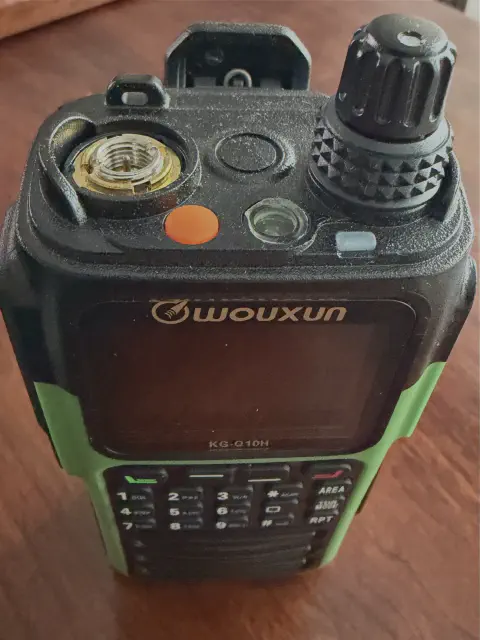 wouxun kg q10h front top view showing sma m connector without antenna black and green body single stacked control knob flashlight lcd display control buttons numeric keypad speaker grille